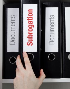 Hand removing subrogation lawyers file/folder from the shelf
